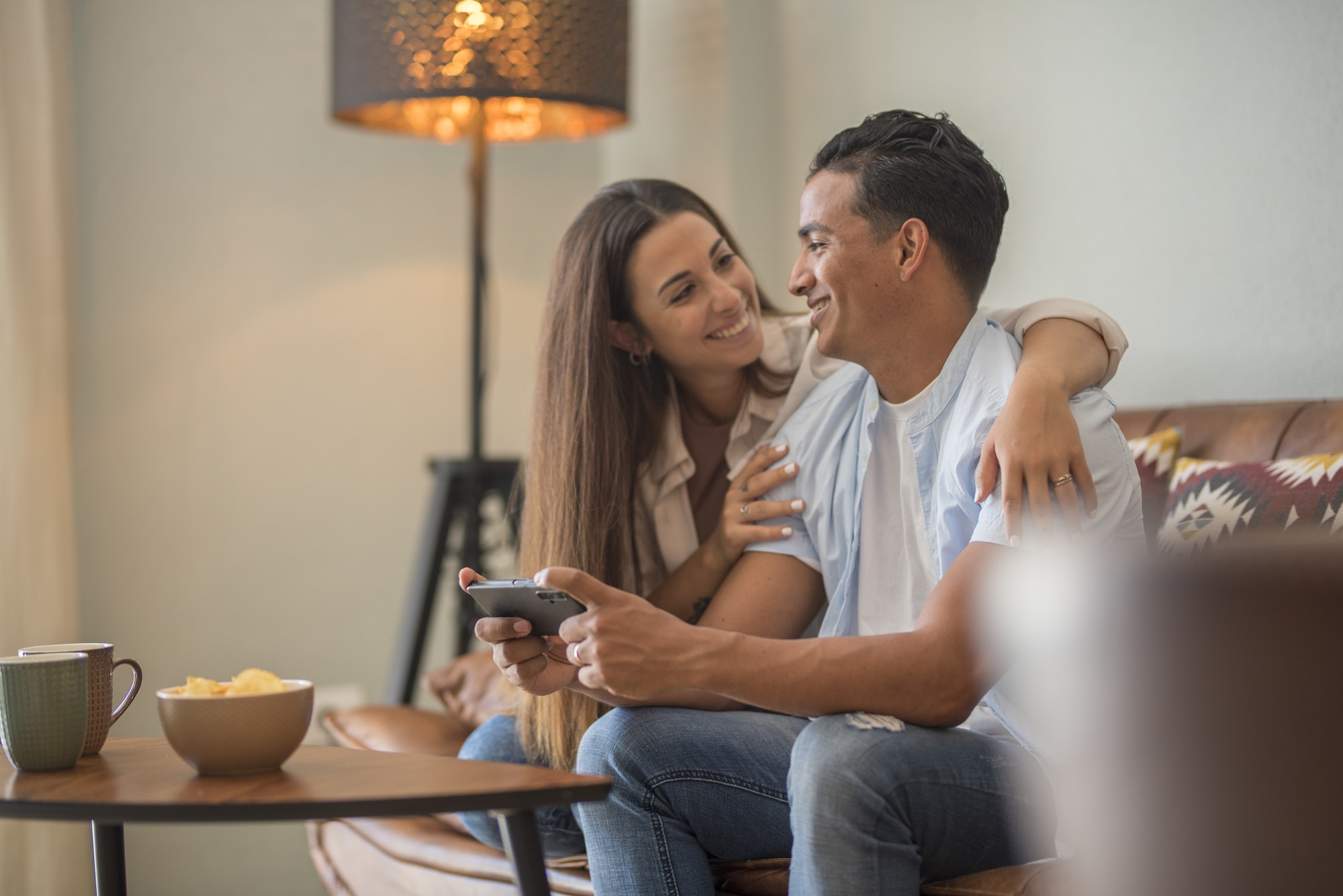 Couple in love resting on comfy couch having fun using smart phone apps, enjoy distant video call